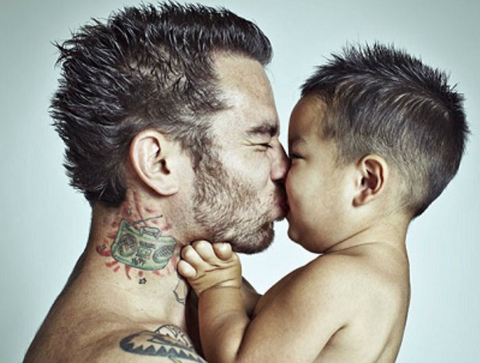 Отец в татуировках ласкает своего ребенка.