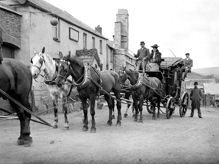 Упряжка коней везет повозку мимо гостинницы Блю-Болл в Каунтисбьюри, Девон, Англия.