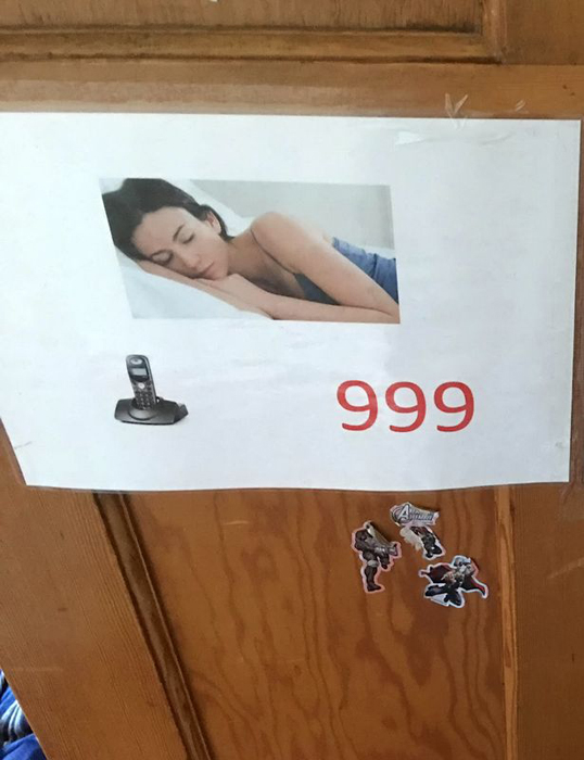 Плакат, висящий в комнате у Тейта, на котором написано, по какому номеру нужно звонить в случае необходимости.