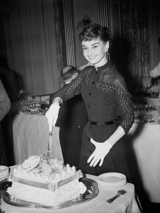 Одри Хепберн позирует с тортом во время коктейльной вечеринки в ее честь.