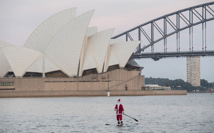 Мужчина в костюме Санты ранним утром в заливе Сиднея. 25 декабря 2016. Фото: James D. Morgan.