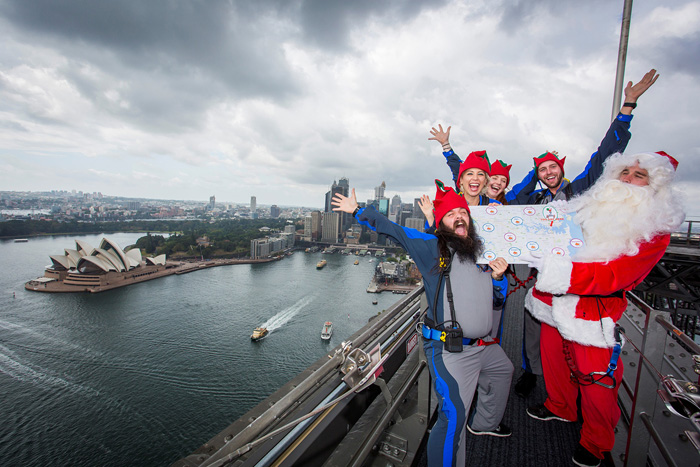 Люди, одетые в костюмы помощников Санты и самого Санту стоят на вершине моста Харбор-Бридж в Сиднее. 7 декабря 2016. Фото: BridgeClimb Sydney.