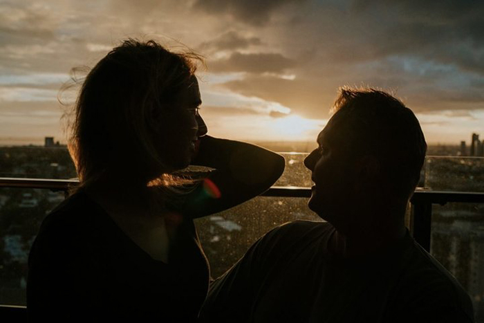 Стеф и Роб стоят на балконе своей квартиры в лучах заходящего солнца.  Фото: James Day.