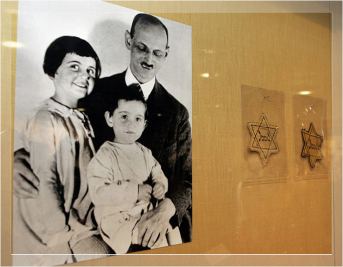 Фотография Отто Франка с его дочерьми Анной и Марго, рядом с жёлтыми звёздами, которые заставляли носить голландских евреев.