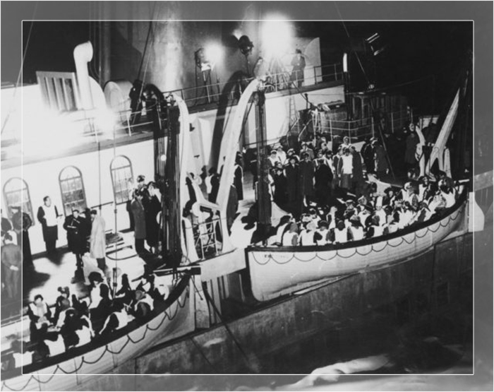 Переполненные спасательные шлюпки спускают с потерпевшего крушение Титаника в сцене из фильма Роя Уорда Бейкера 1958 года «Незабываемая ночь».