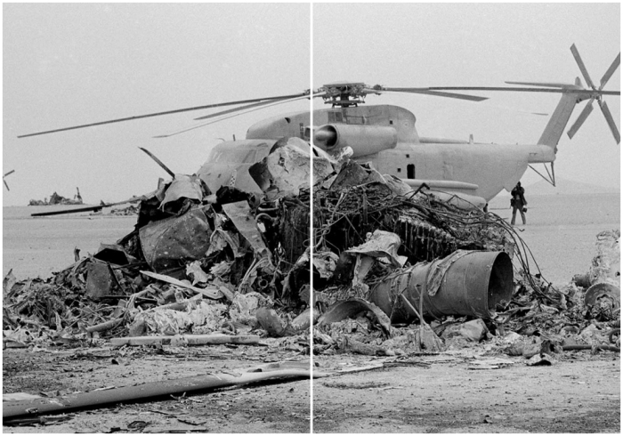 Оперативный вертолет стоит рядом с обугленными останками одного из вертолетов спасательной миссии.