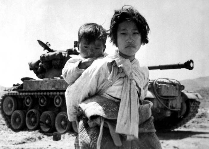 Кореянка с младшим братом на спине устало тащится мимо заглохшего танка М-26 в Хенджу, Корея, 9 июня 1951 года. \ Фото: bing.com.