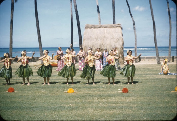 Группа девушек танцует танец хула с яркими цветами в волосах и на шее.
