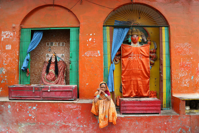 Женщина сидит возле храма почитания индийских божеств.