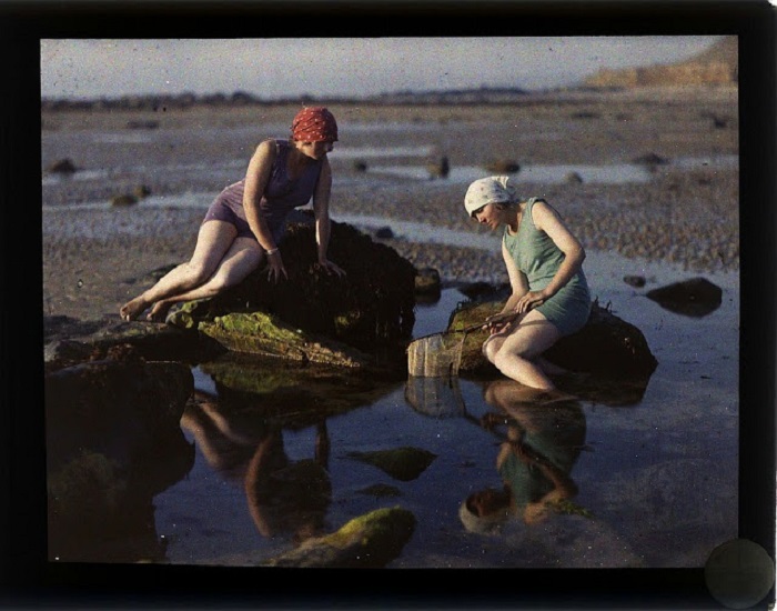 Женщины ловят рыбу на мелководье.