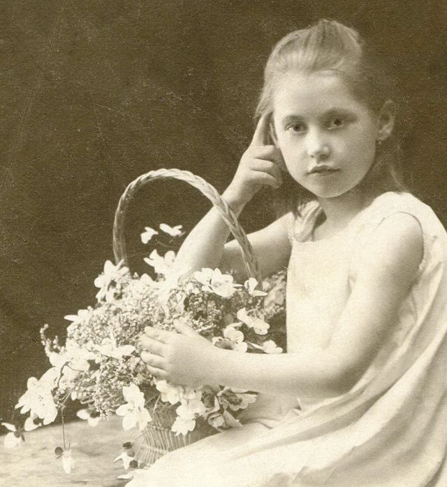 Девочка позирует в легкой одежде с корзиной цветов.