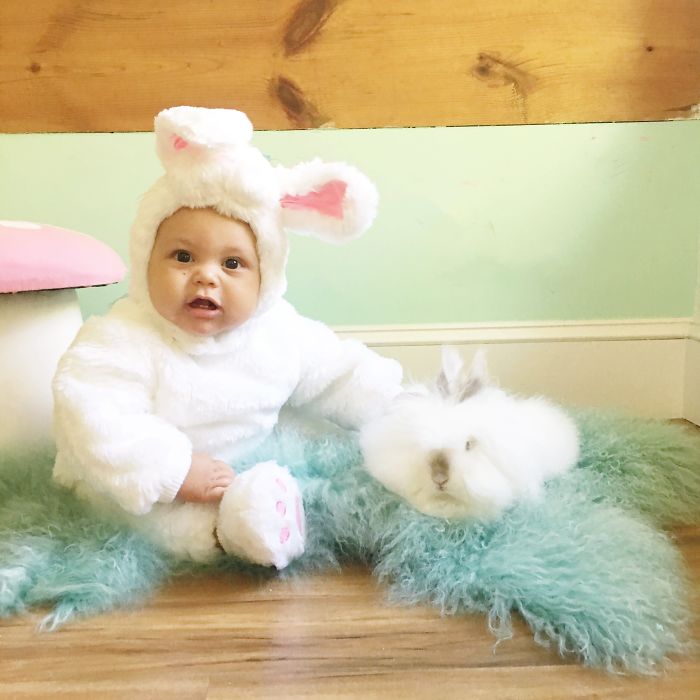 Карапуз в костюме зайца держит кролика.