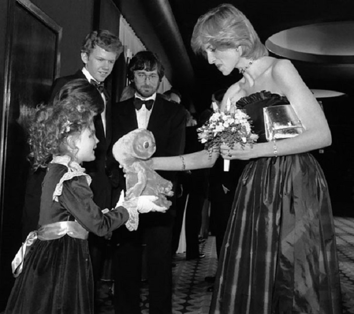 7-летняя Дрю Бэрримор дает Принцессе Диане игрушку, а в это время позади них стоят молодые знаменитости Роберт Макнотон и Стивен Спилберг.