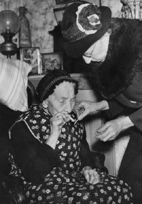 75-летняя Мэри Пэриш прикуривает сигарету для ее 101-летней матери, Мэри Энн Пэриш. Валворт, Лондон, 14-го февраля 1946 года.