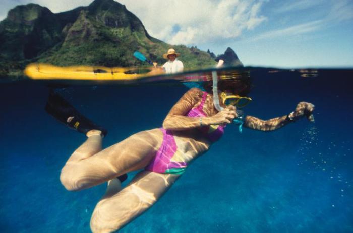 Женщина ныряет в национальном парке of Na Pali Coast у побережья острова Кауаи на Гавайях.