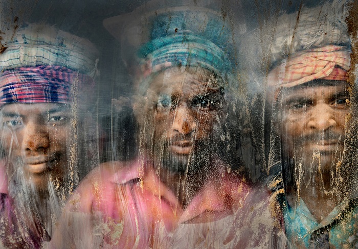 Работа Файзаль Азим (Faisal Azeem), занявшая второе место, категория «Портреты из путешествий». Трое мужчин, работающих на производстве гравия в Бангладеш, смотрят через грязное и пыльное стекло.