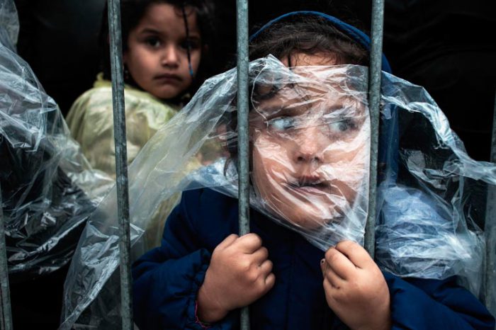 Девочка в дождевике ждет регистрацию в лагере для беженцев.