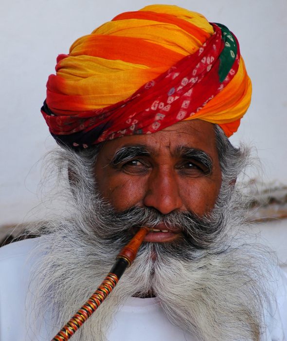Пожилой индиец в ярком тюрбане с трубкой от кальяна.
