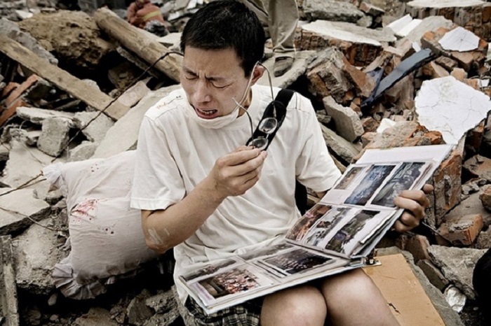 Мужчина из Китая плачет, найдя семейный альбом среди разрушенного своего дома после землетрясения.