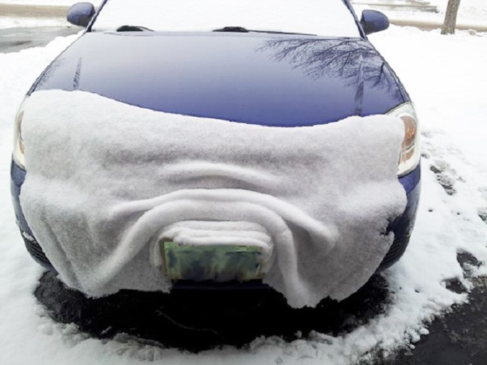 Слой снега покрыл бампер машины.