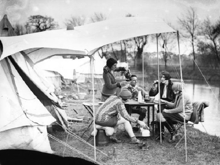 Чаепитие туристов за установленным столом и палаткой на фоне чудесного пейзажа.