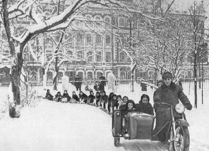 Катание детей по снегу в импровизированном «санном поезде».