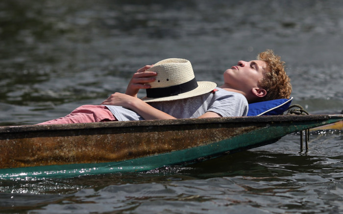 Парень, уснувший в лодке на Хенлейской королевской регате в городе Хенли-он-Темз, Англия.