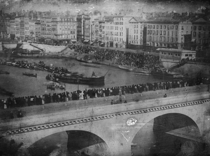 Большая толпа смотрит водный турнир на реке Сона в Лионе (первая спортивная фотография) в 1842 году.  