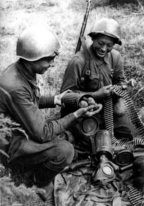  Русские солдаты осматривают трофеи, взятые у немцев и обнаруживают в футляре для противогаза картофель. 1941 год. 