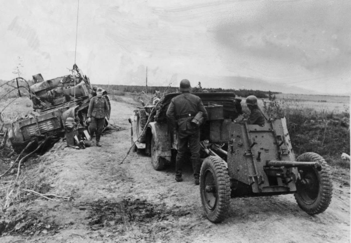  Немецкие артиллеристы осматривают останки тяжелого артиллерийского тягача Ворошиловец. 1941 год.  