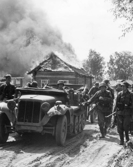 Тягач Sonderkraftfahrzeug и солдаты дивизии СС проезжающие через деревню. 1941 год. 