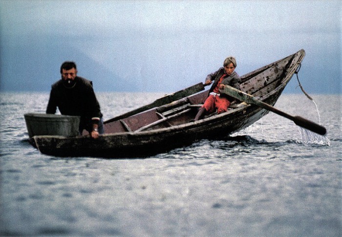 Рыбак Вячеслав Басов ставит сети, в то время как его 10-летний сын управляет лодкой.