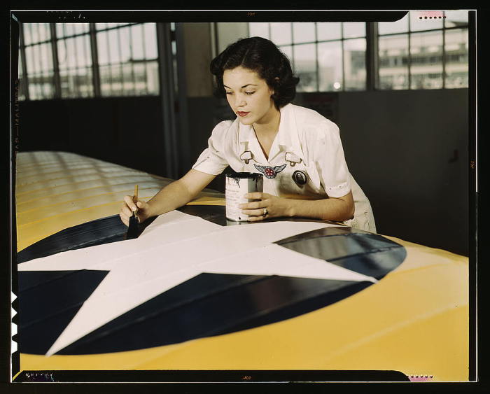 Сотрудница гражданской службы на Военно-морской авиабазе рисует знаки на крыльях самолета. США, штат Техас, 1942 год. 