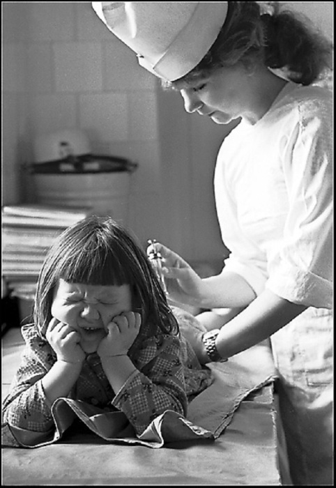 Медсестра, делающая девочке болючий укол. 