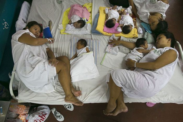 Несколько матерей с новорожденными детьми на одной кровати. 