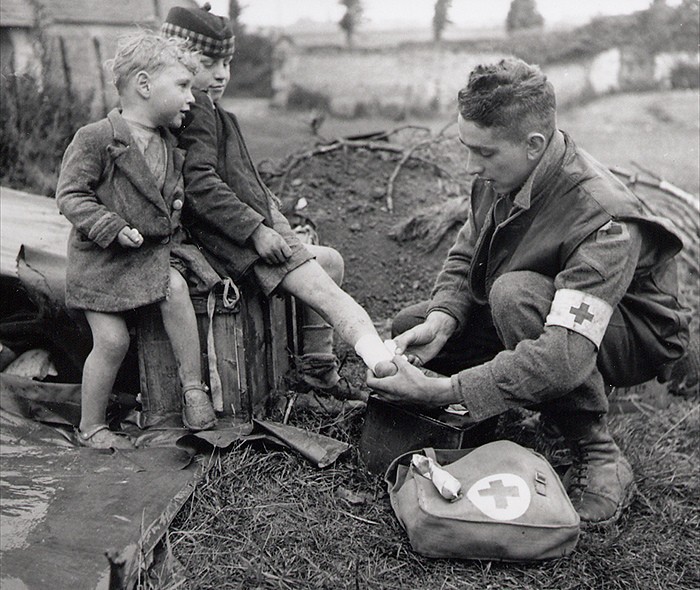 Канадский врач накладывает бандаж на ногу раненого ребенка, 1944 год.