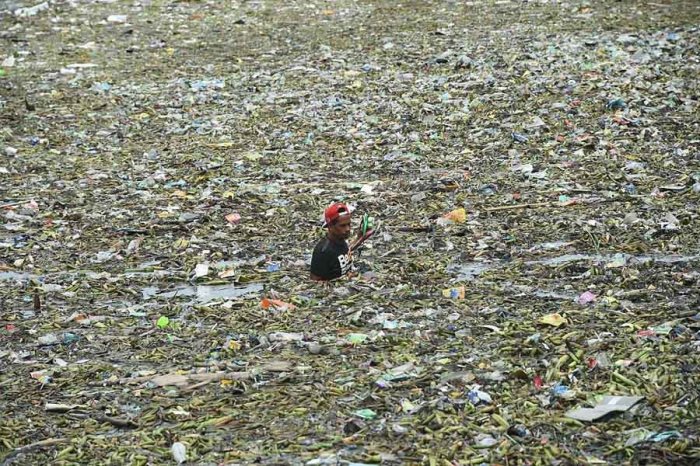 Человек собирает перерабатываемые материалы среди плавающего мусора после тропического шторма Нида.