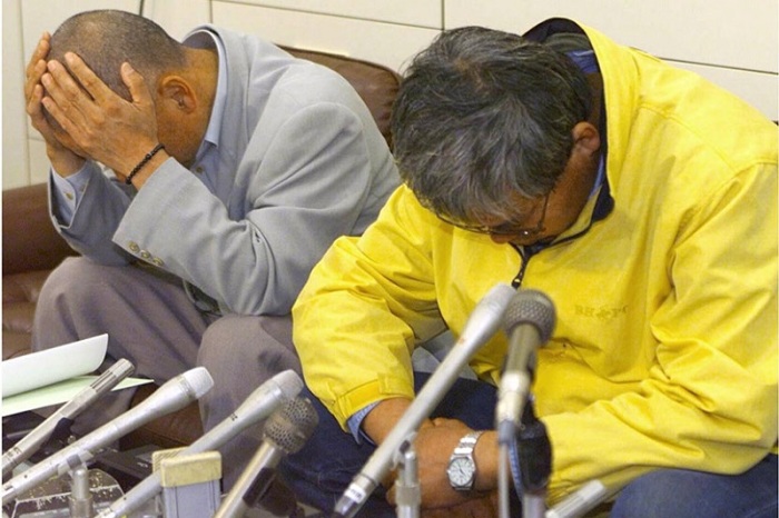 На пресс-конференции лжеученый (справа, в желтой куртке) сидел, опустив голову, и стыдился посмотреть в глаза журналистам.