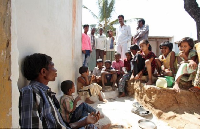 Мужчина показывает местным жителям, как он ест камни и песок.