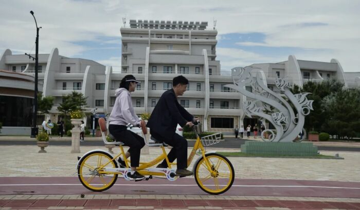 Туристы катаются на тандемном велосипеде возле бассейна курорта Вонсан-Кальма. Туристы катаются на тандемном велосипеде возле бассейна курорта Вонсан-Кальма.