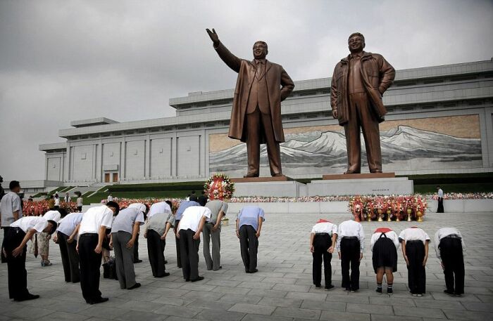 Северокорейцы склоняются перед бронзовыми статуями Ким Ир Сена (слева) и Ким Чен Ира на холме Мунсу. Северокорейцы склоняются перед бронзовыми статуями Ким Ир Сена (слева) и Ким Чен Ира на холме Мунсу.