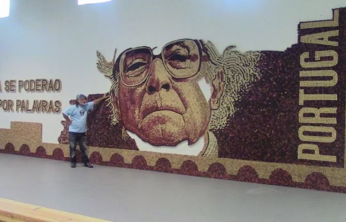 Художник позирует на фоне созданного им портрета писателя Жозе Сарамаго, сделанного из пробок